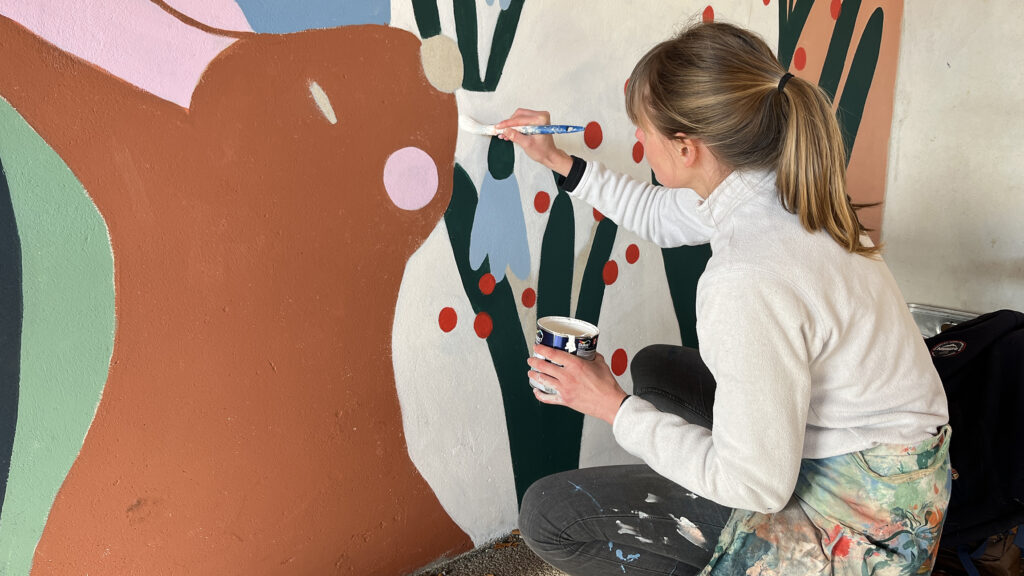 Photo d'une femme en train de peindre une fresque murale