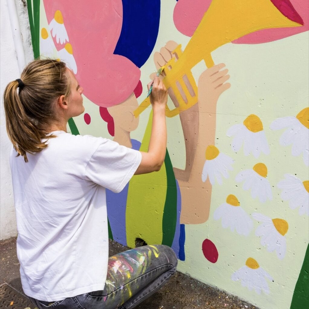 Photo d'une peintre muraliste en train de réaliser une fresque à Mondeville