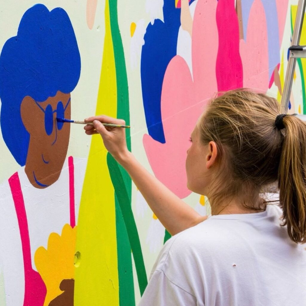 Photo d'une illustratrice en train de peindre une fresque en Normandie